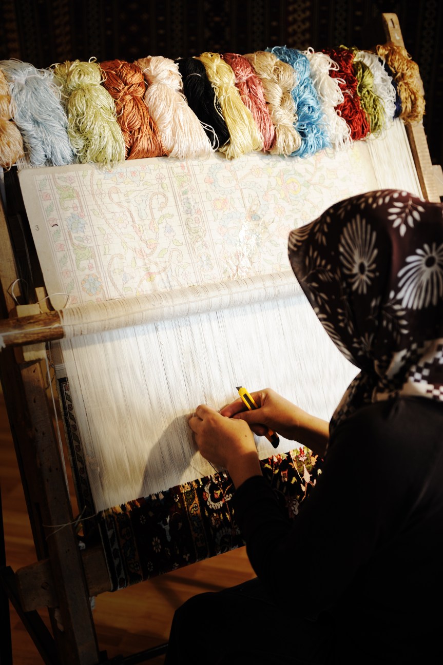 Woman working at the loom. Oriental Muslim national crafts. Focus on the fabric.